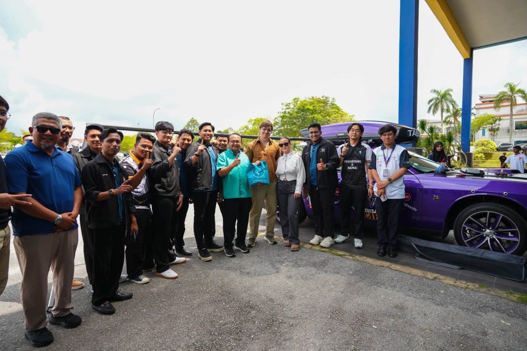 Convoy participants gathered beside a purple Dodge Challenger at UMPSA Paya Besar.